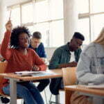 Happy African American woman raising her hand in class.